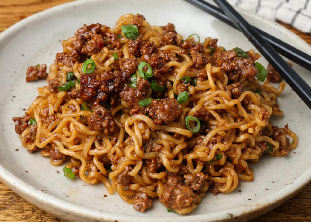 Korean beef noodles on a plate with a checked white and navy linen