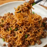 Korean beef noodles on a plate with a checked white and navy linen and chopsticks