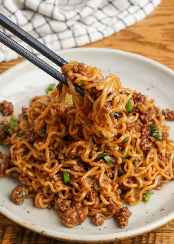 Korean beef noodles on a plate with a checked white and navy linen and chopsticks