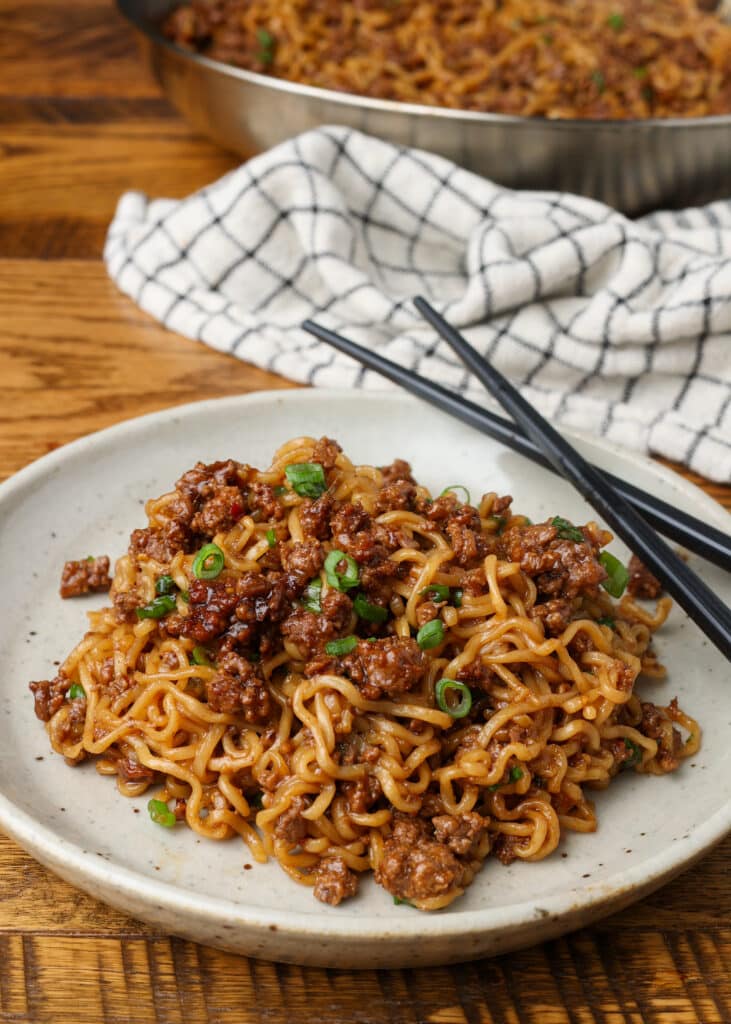 Korean beef noodles on a plate with a checked white and navy linen and chopsticks
