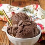 small white bowl with scoops of chocolate ice cream and a gold spoon