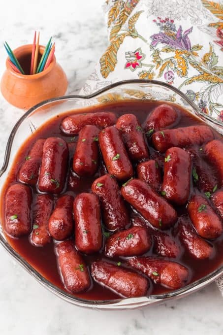 A bowl of cocktail sausages, toothpicks and a napkin.