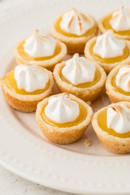 A plate of cookie cups filled with lemon curd with browned frosting.