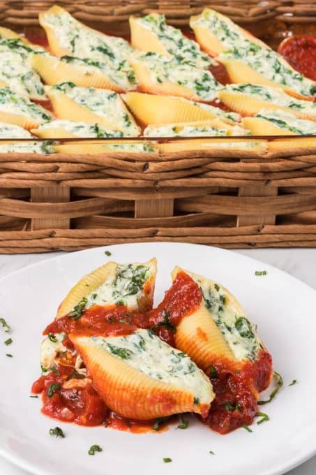 Marina covering pasta shells with ricotta spinach filling on a plate.