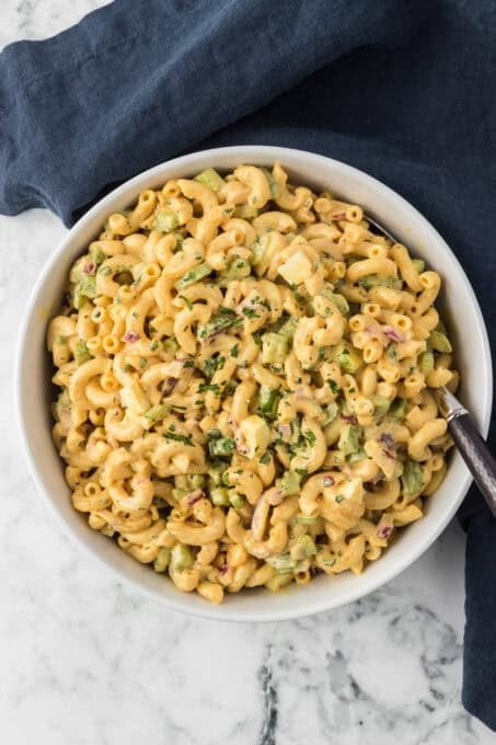 A serving bowl full of a salad with macaroni.