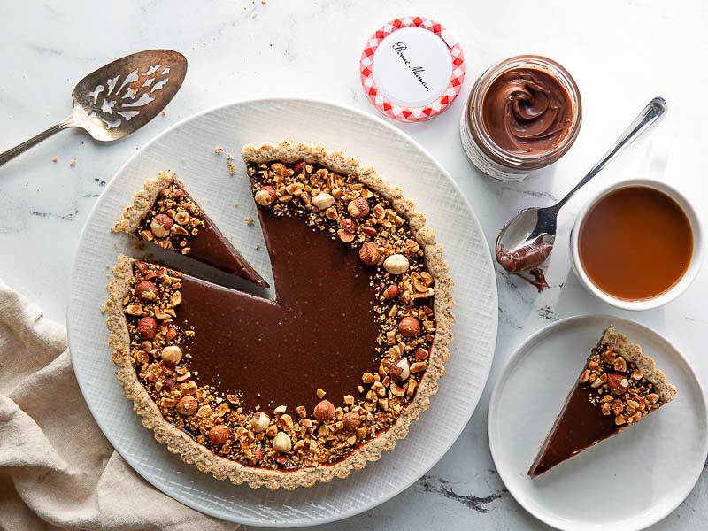 chocolate hazelnut tart overhead sliced on white plate