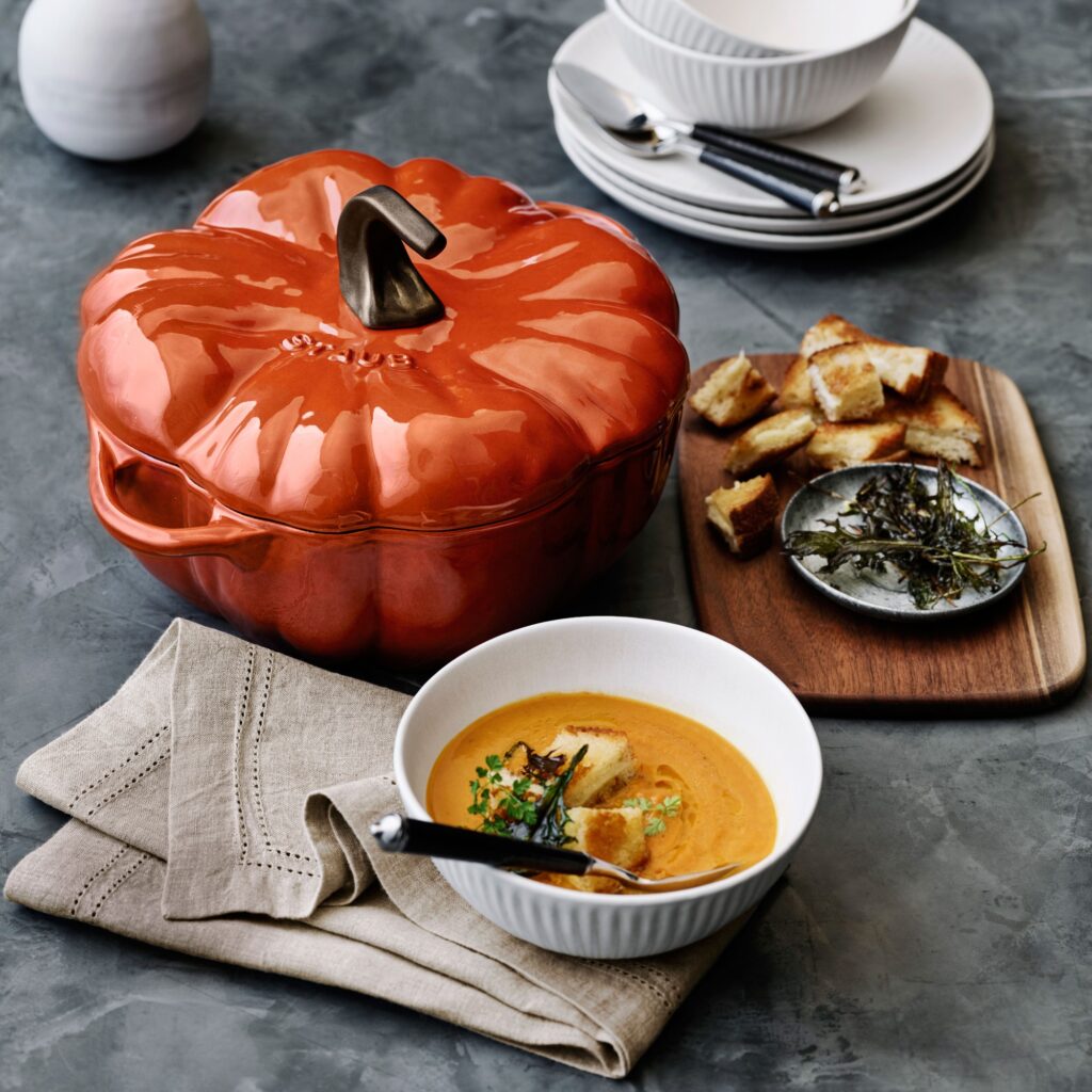 Pumpkin dish next to bowl of soup and bread serving tray