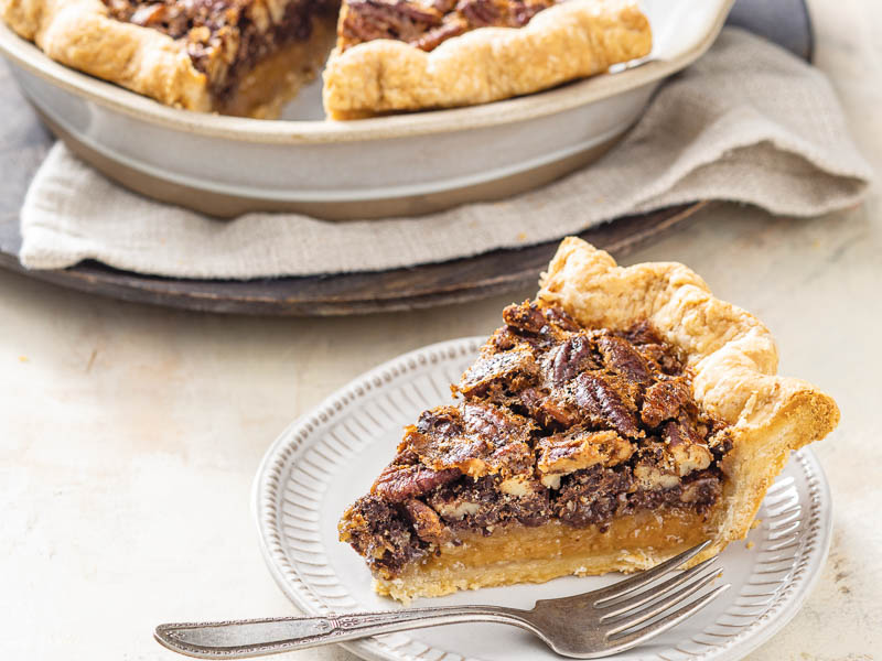 Deep dish chocolate chunk pecan pie sliced on white plate with fork