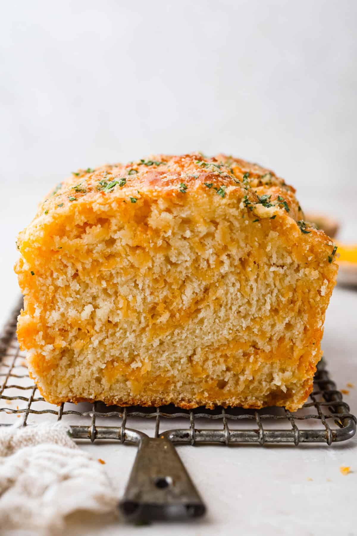 Cheddar bay biscuit bread loaf cut in half on a cooling rack. 
