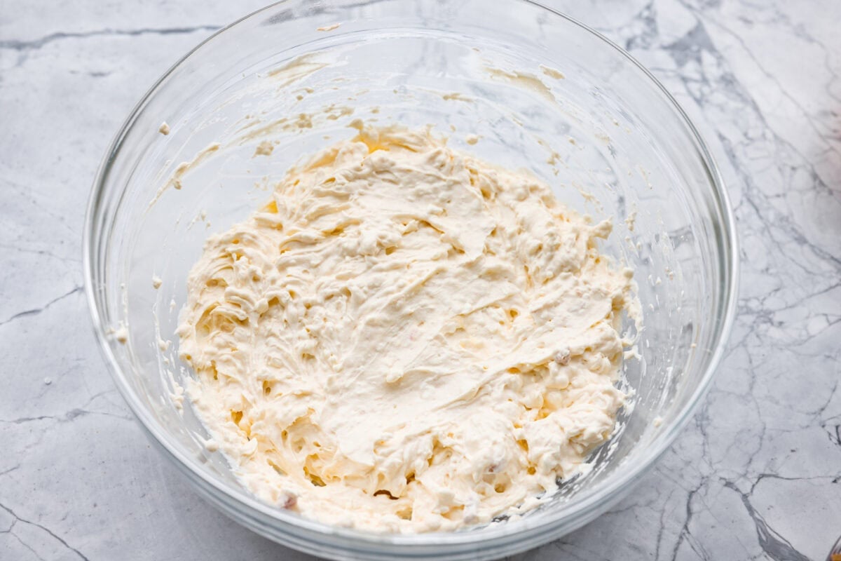 Cream cheese, cream of chicken soup, and sour cream all mixed together in a mixing bowl.