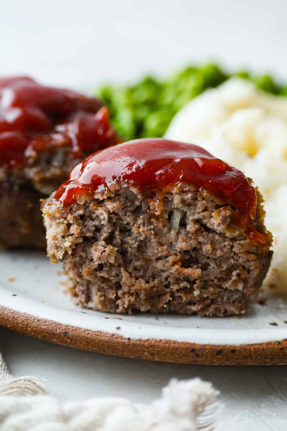 Mini meatloaf cut through the center vertically so you can see al the juicy meat and onions and tangy glaze on top. 