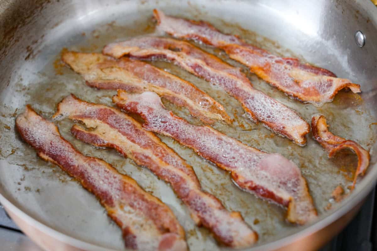 Bacon cooking in a skillet. 
