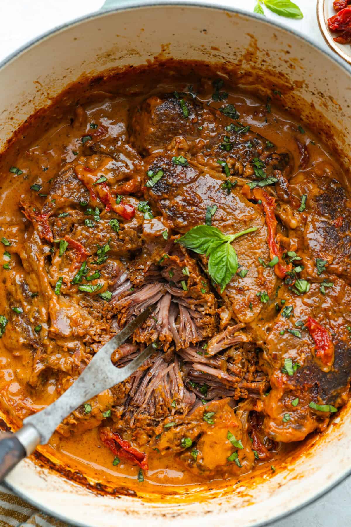 Overhead shot of a dutch oven with Marry Me Pot Roast all cooked and sitting in a rich velvety sauce. 