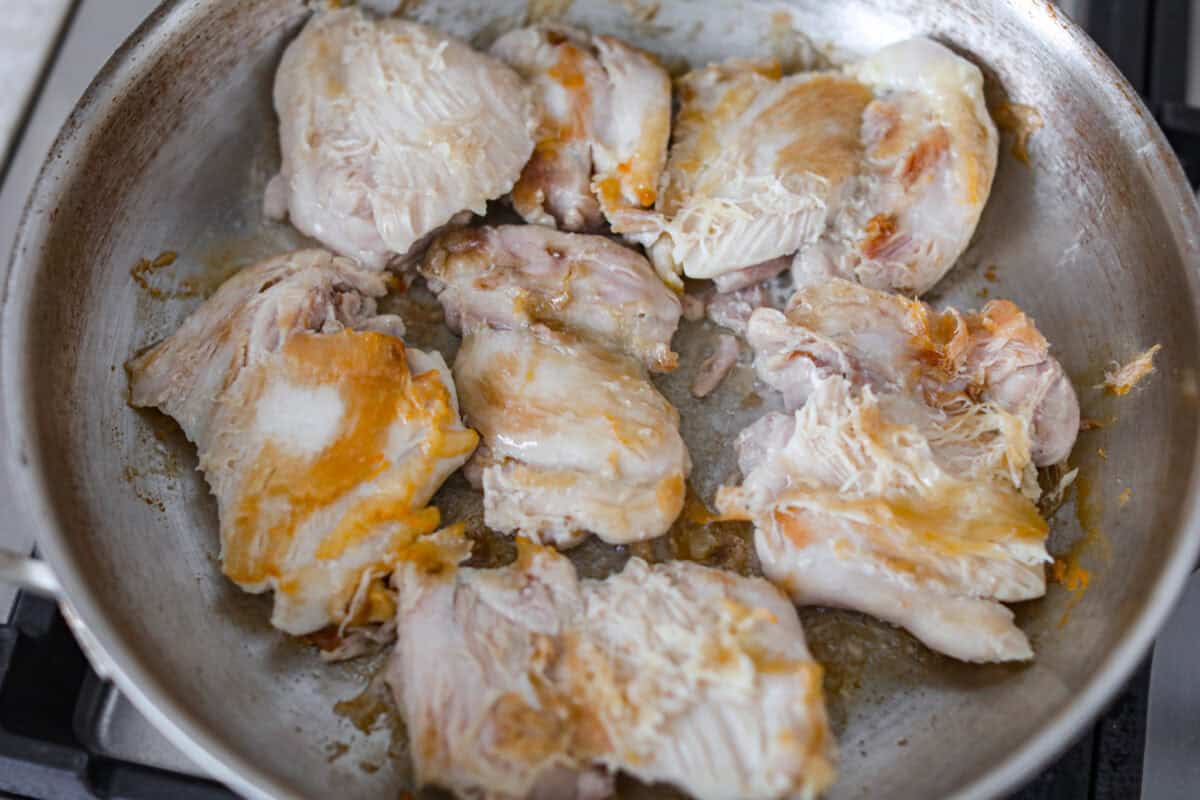 Chicken thighs browning in a pan. 