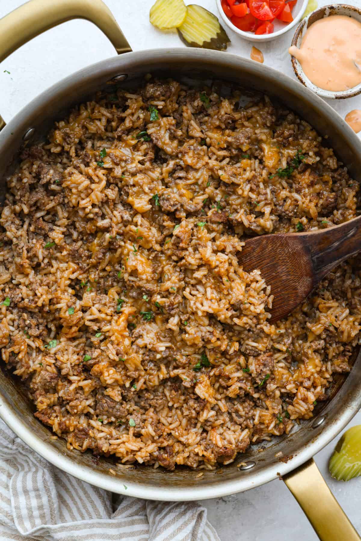 Skillet of cheeseburger rice with a wooden spoon. 