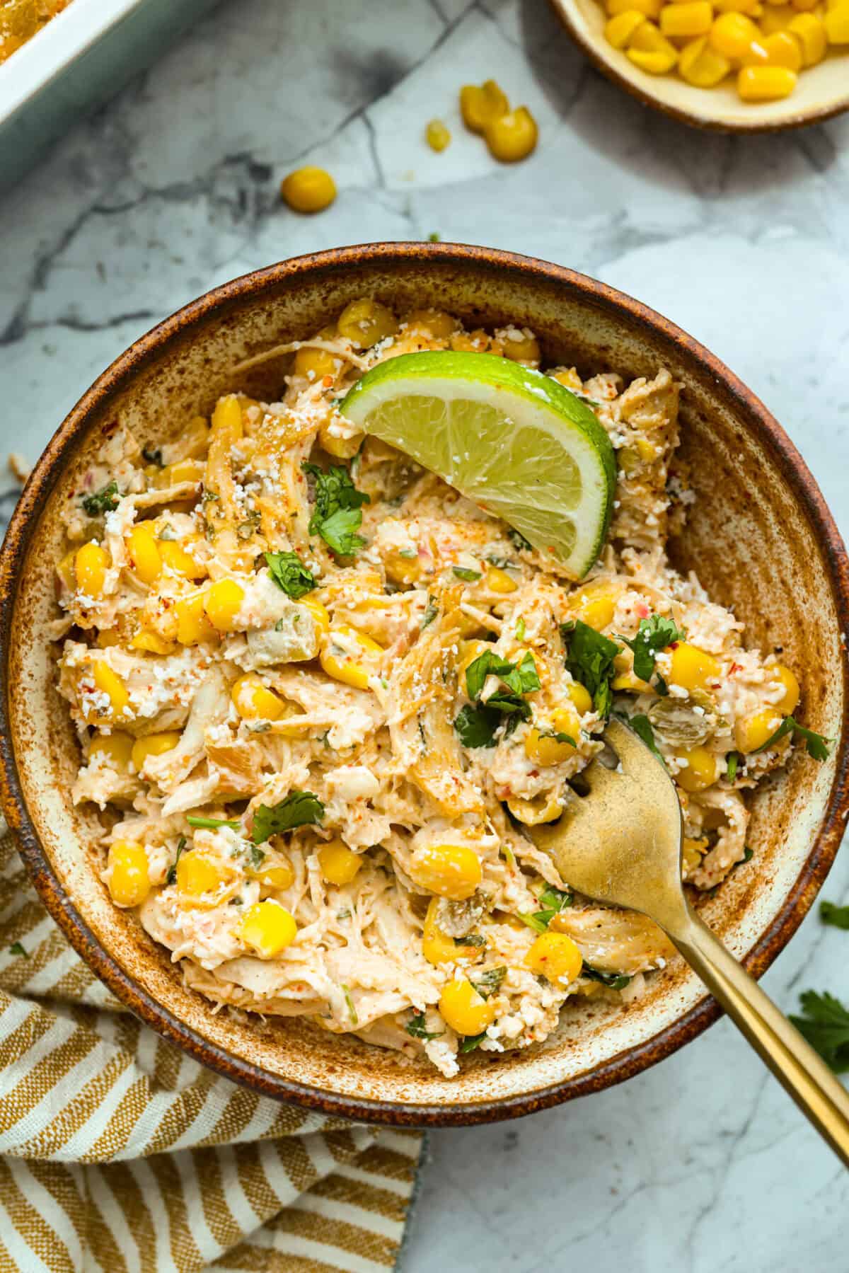Serving of the Mexican street corn chicken casserole in a bowl with a gold fork. 
