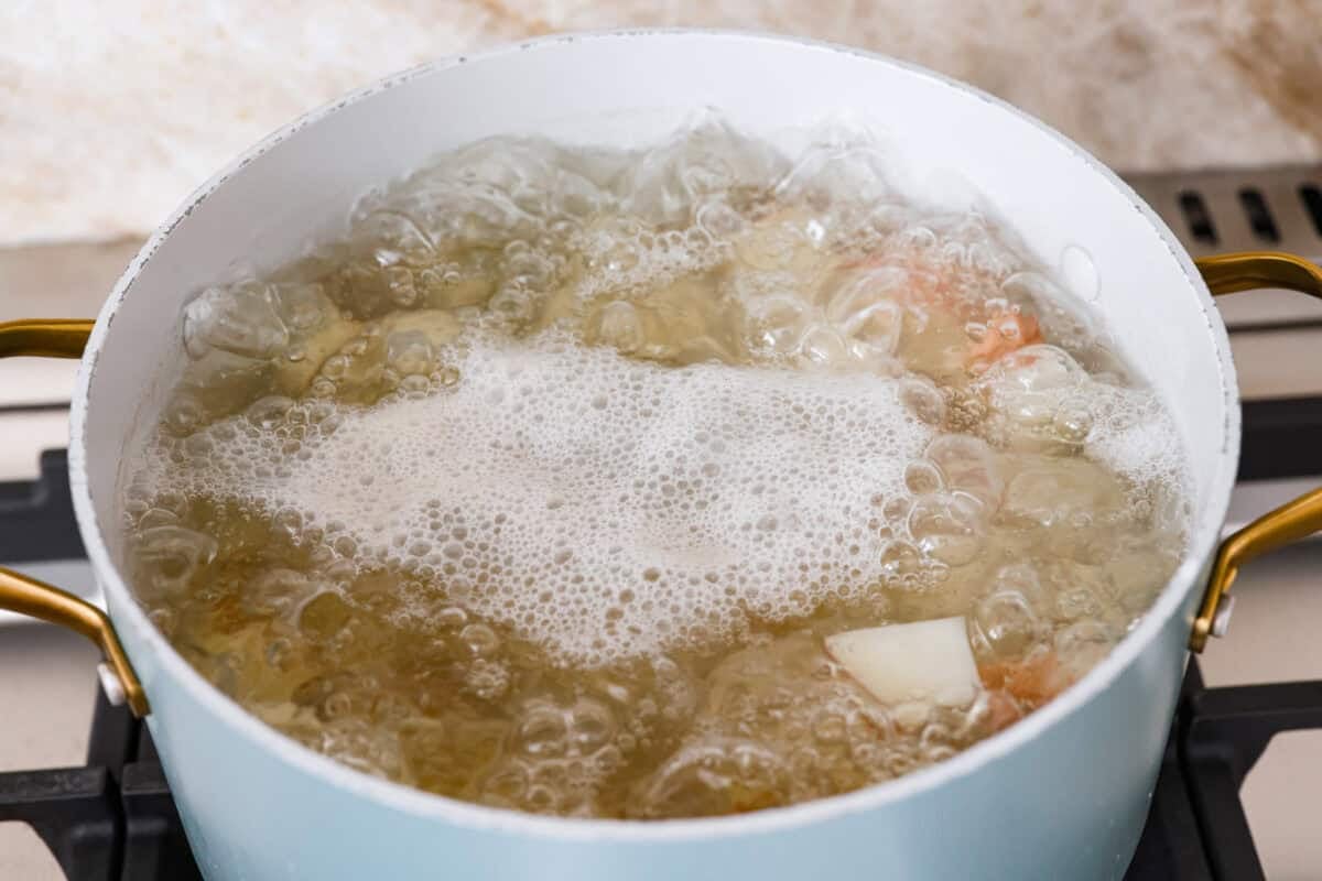 Pot of boiling water with diced potatoes cooking in it. 
