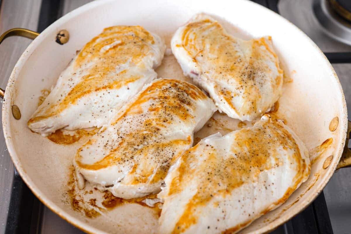 Chicken breasts searing in a pan. 
