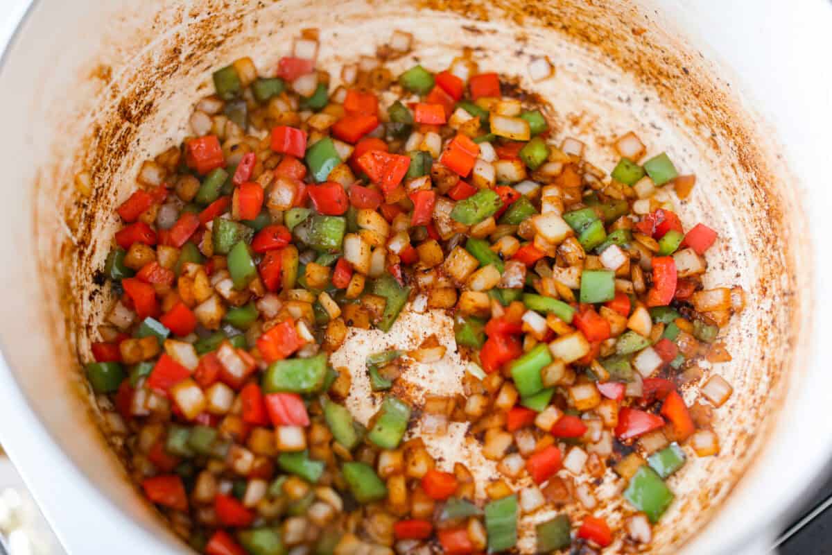 Veggies cooking in bacon grease in a large pot.