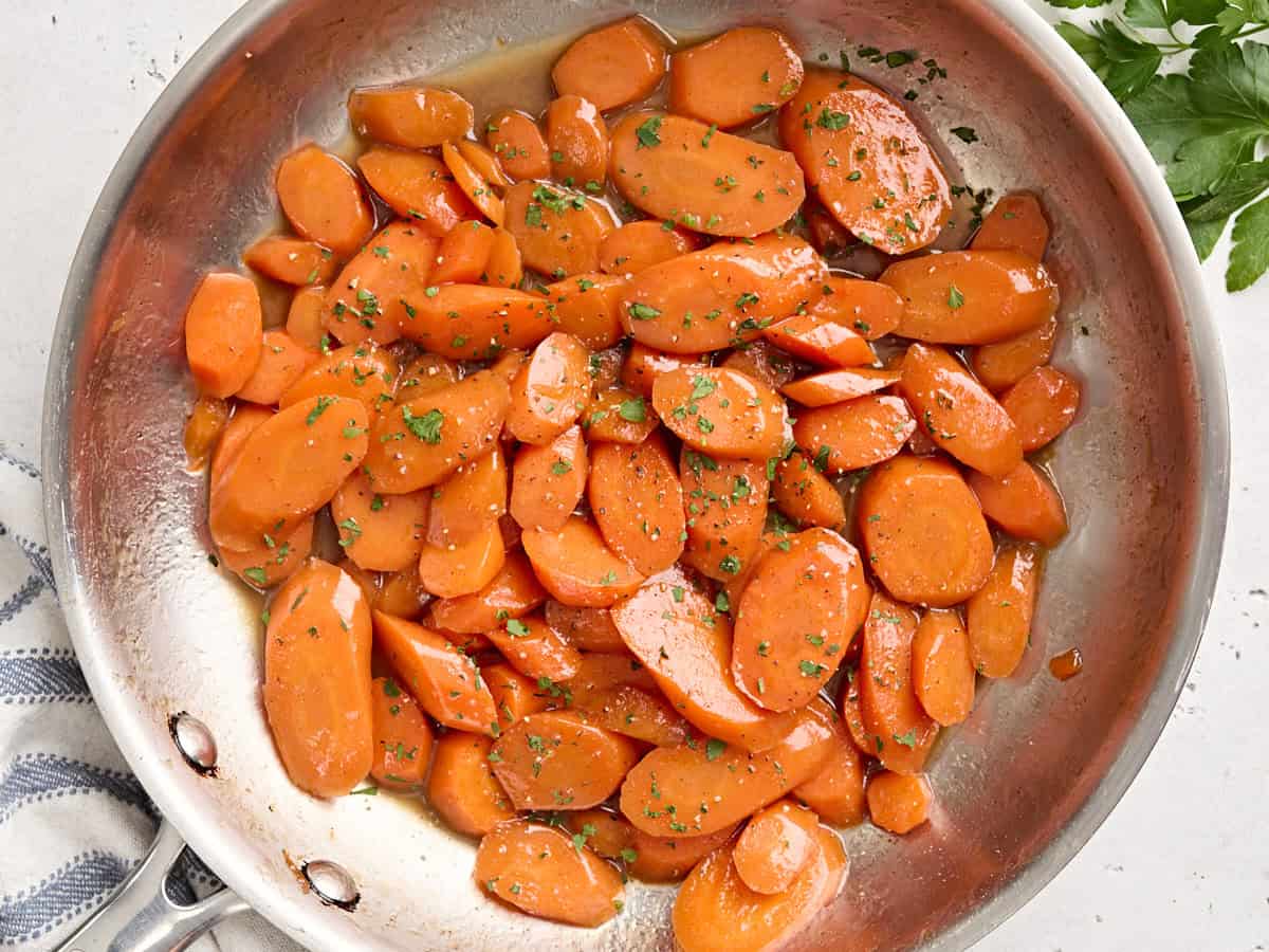 Overhead view of glazed carrots in a saut&eacute; pan.