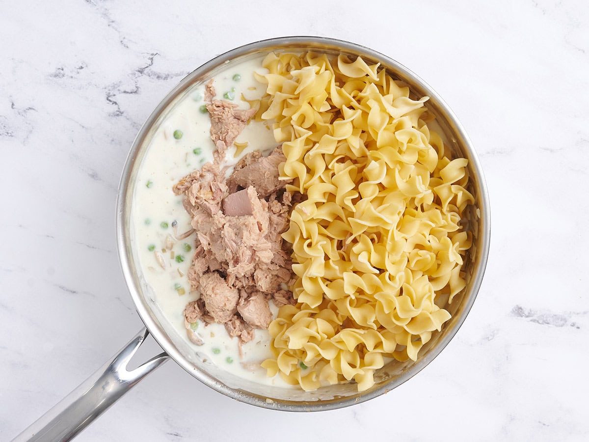 Cooked pasta, tuna, and creamy sauce in a skillet.
