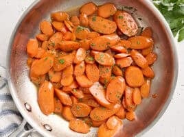 Overhead view of glazed carrots in a saut&eacute; pan.