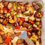 Sheet pan Cajun tofu and vegetables on a baking sheet with a spatula.