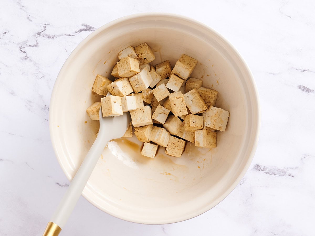 Tofu cubes tossed in soy sauce in a white bowl.