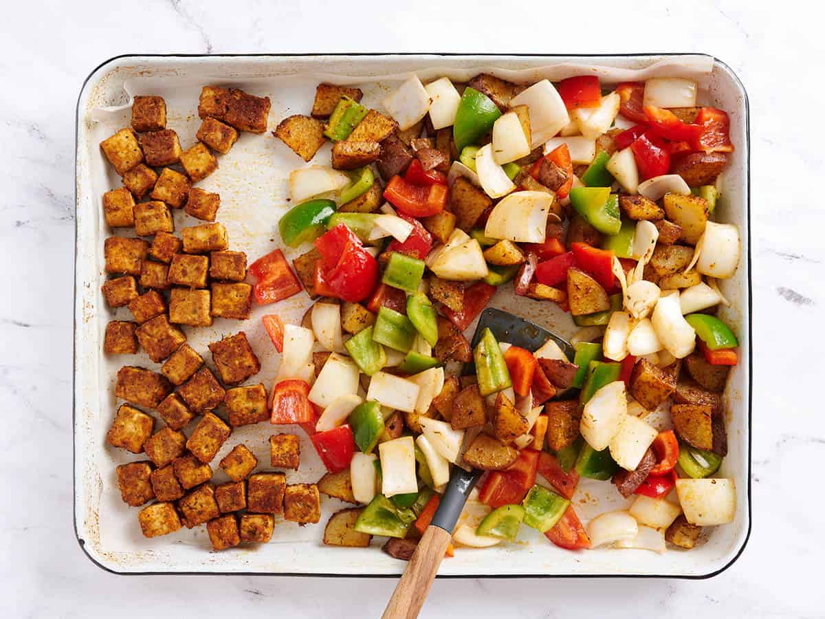 Adding peppers and onion to the sheet pan with the tofu and potatoes.