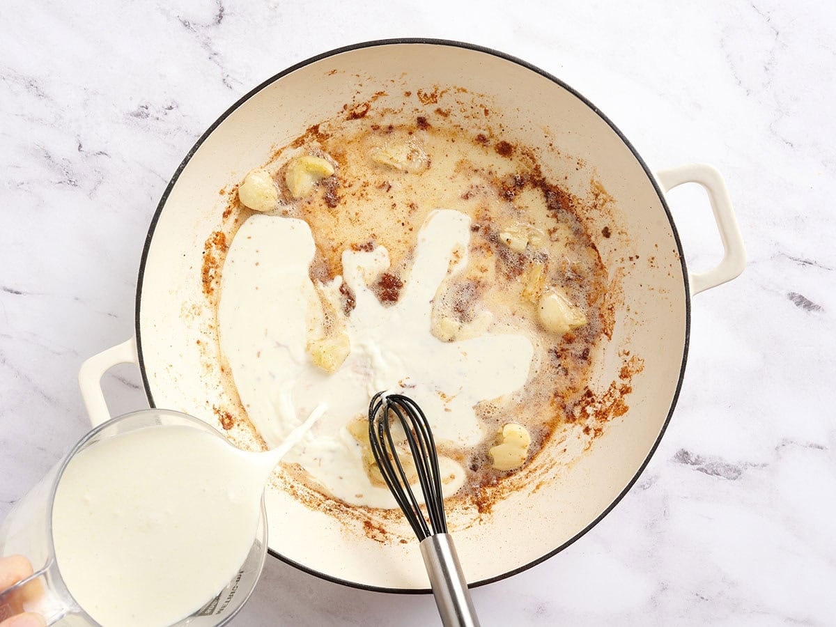 Heavy cream being poured in a skillet.