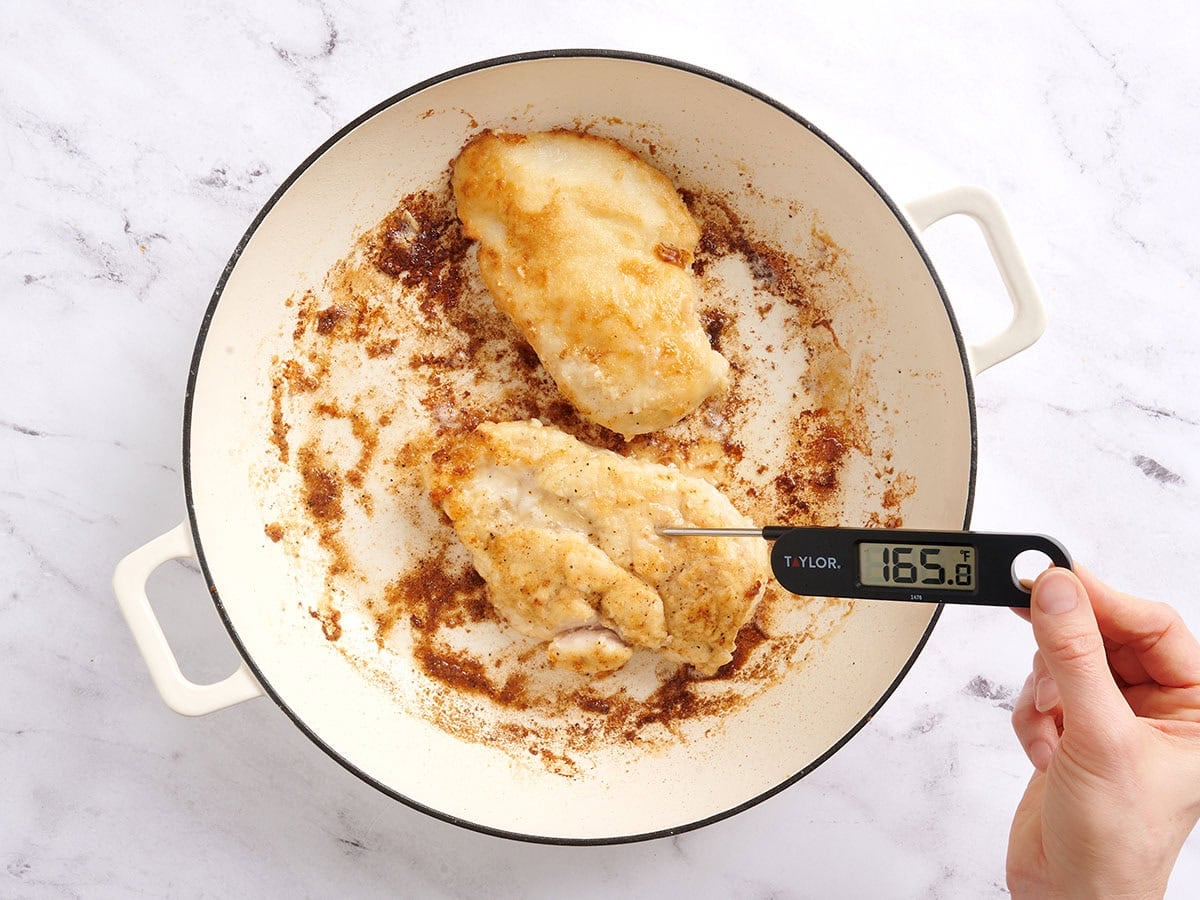A thermometer checking the internal temp of cooked chicken.