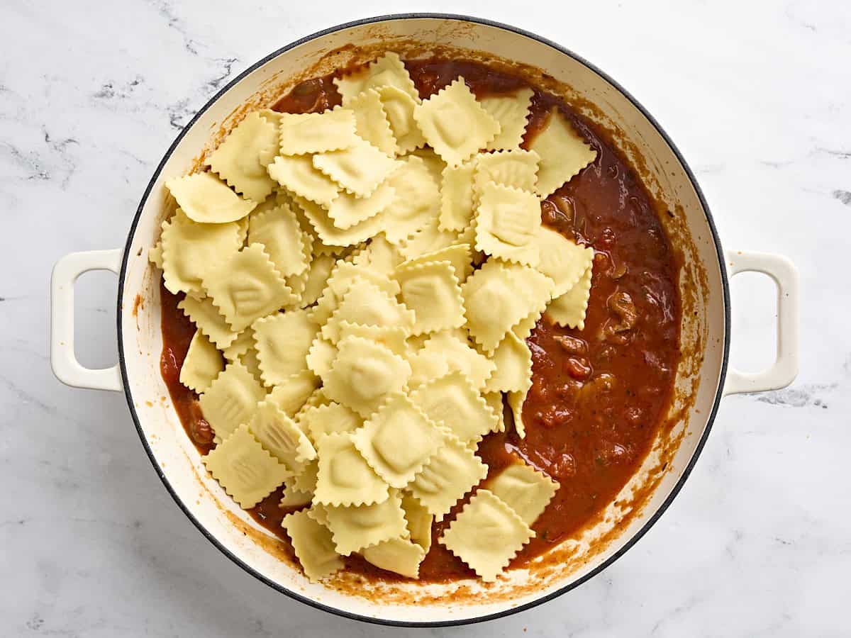 Cheese ravioli added to a skillet with a tomato mushroom sauce.