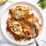 Overhead view of stuffed shells on a white plate with a fork cutting one of the shells in half.