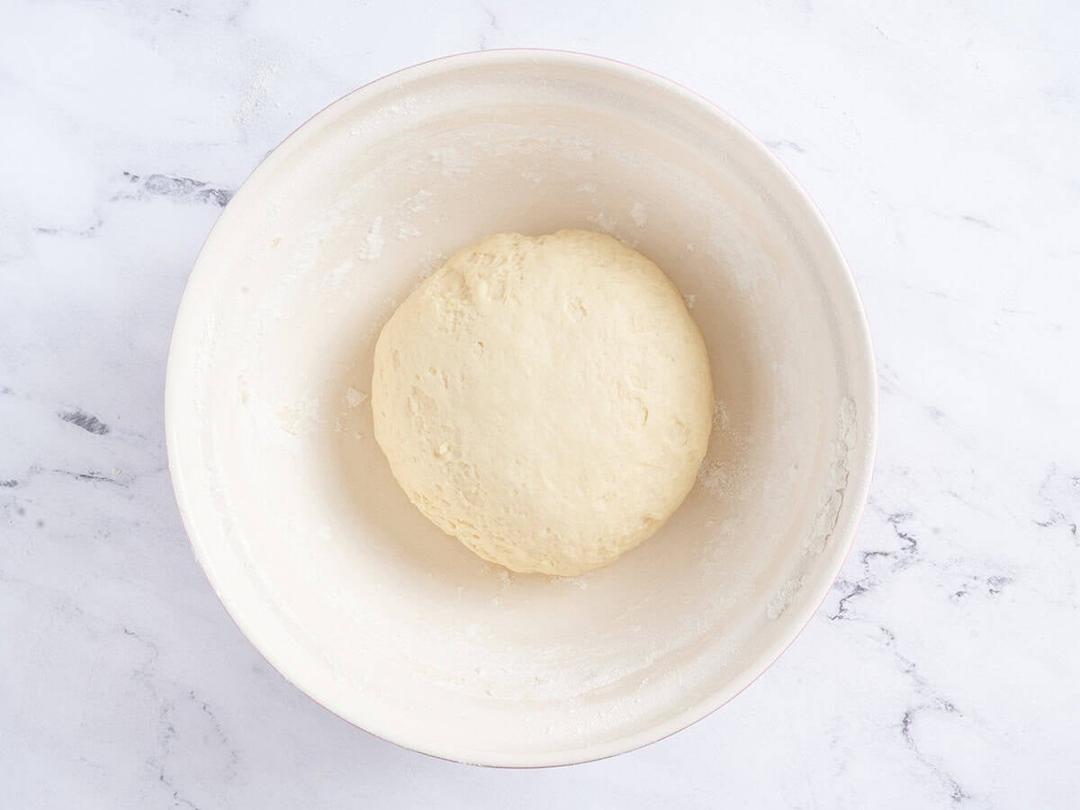 Dough ball in a white bowl just before rising.