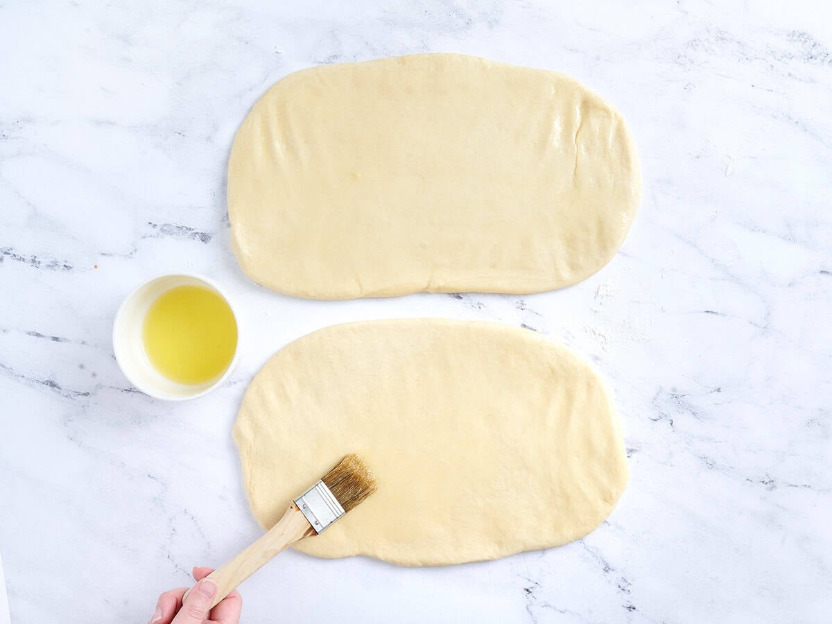 Brushing the rolled out dough with butter.