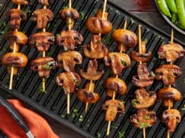 Overhead view of smoky grilled mushroom kebabs on a grill.
