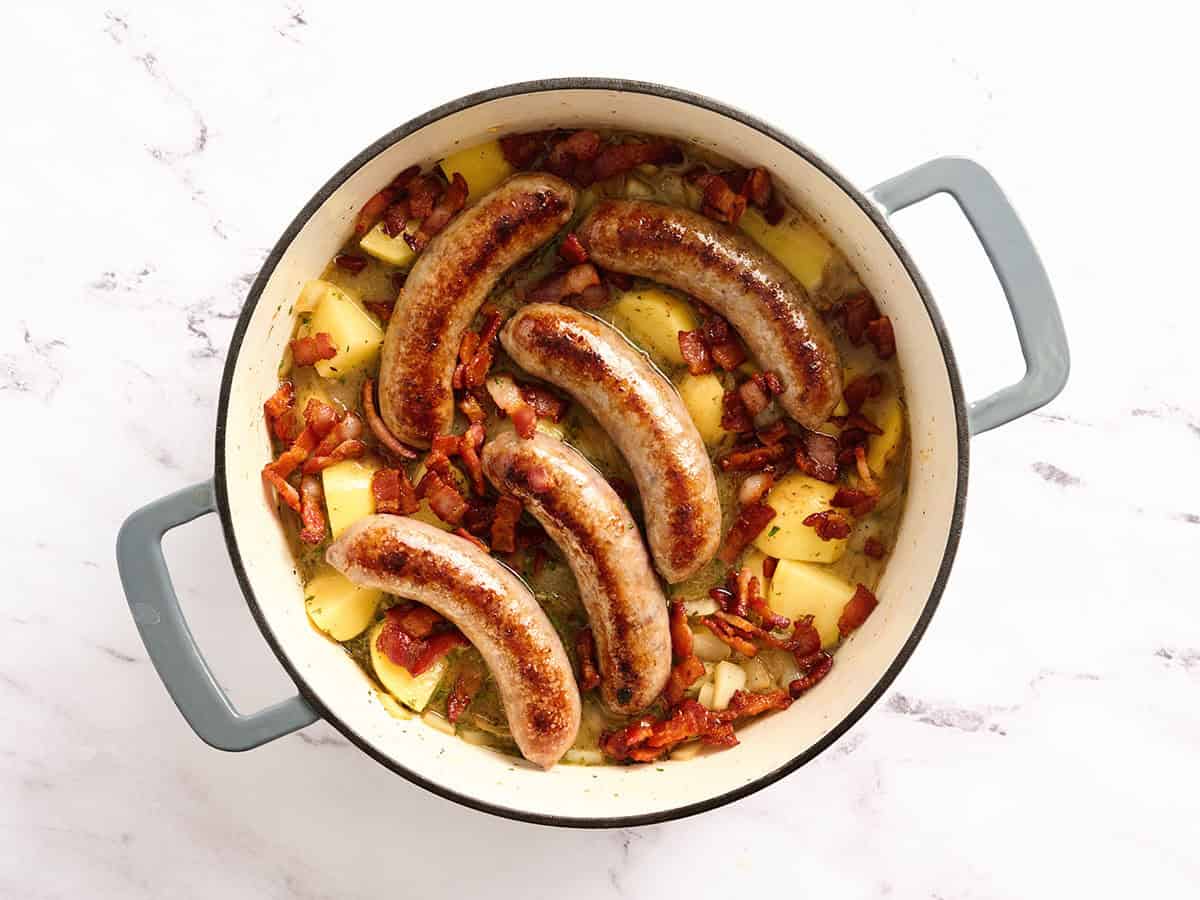 Brats placed on veggies for Dublin coddle in a dutch oven.