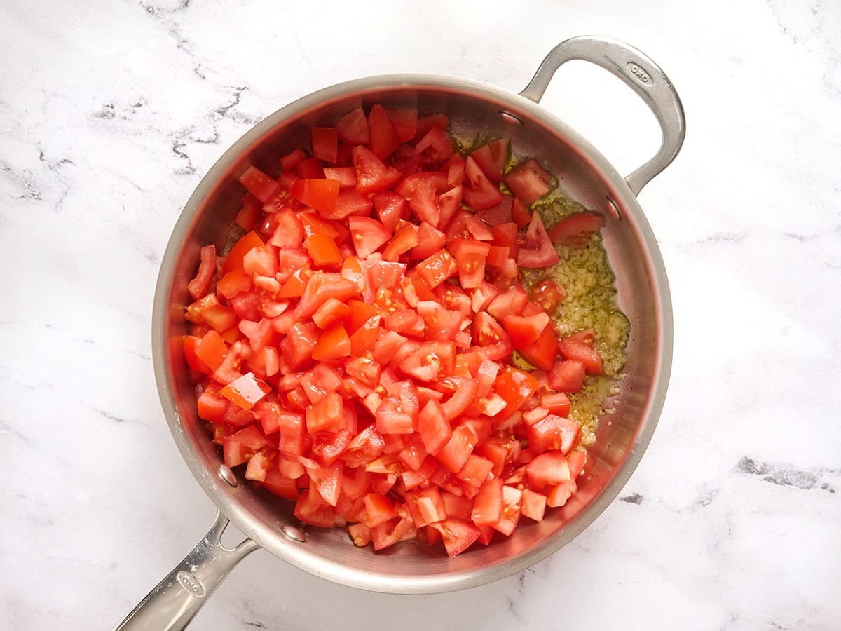 Diced tomatoes added to a skillet.