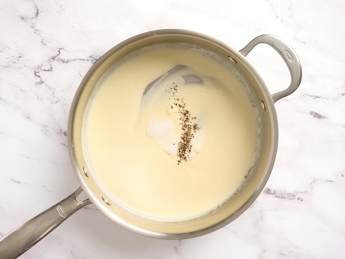 A cream sauce in a skillet with seasoning added.