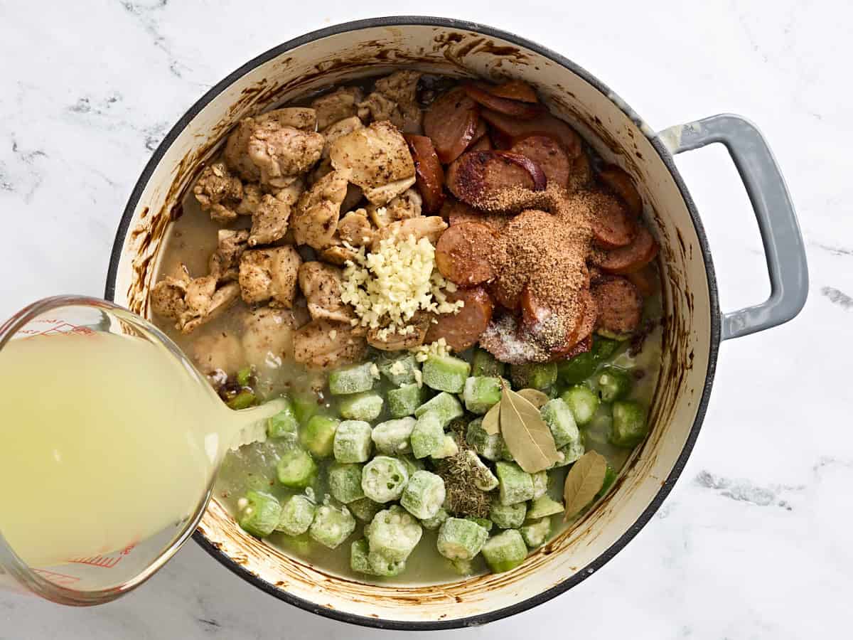 Frozen okra, browned chicken and sausage, seasonings and broth in a pot.