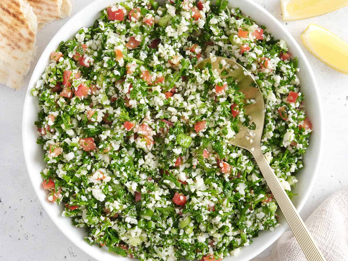 Overhead view of a bowl of cauliflower tabbouleh with a spoon.