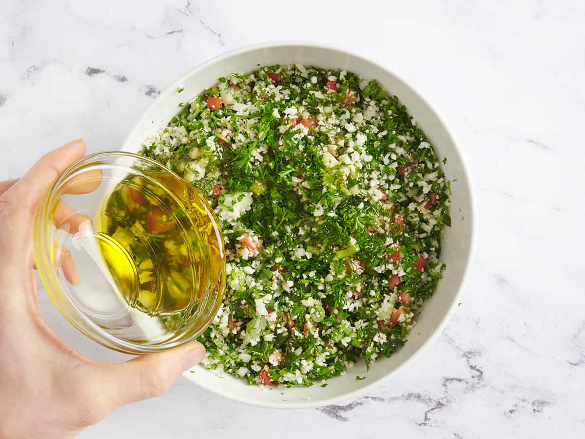 Olive oil being poured into cauliflower tabbouleh.