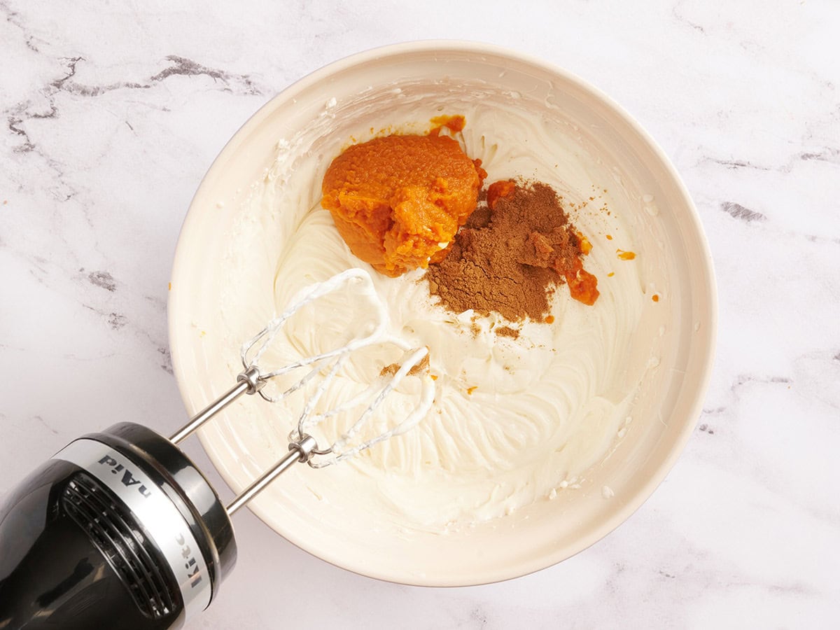 Pumpkin spice and pumpkin puree in a bowl with cheesecake filling.