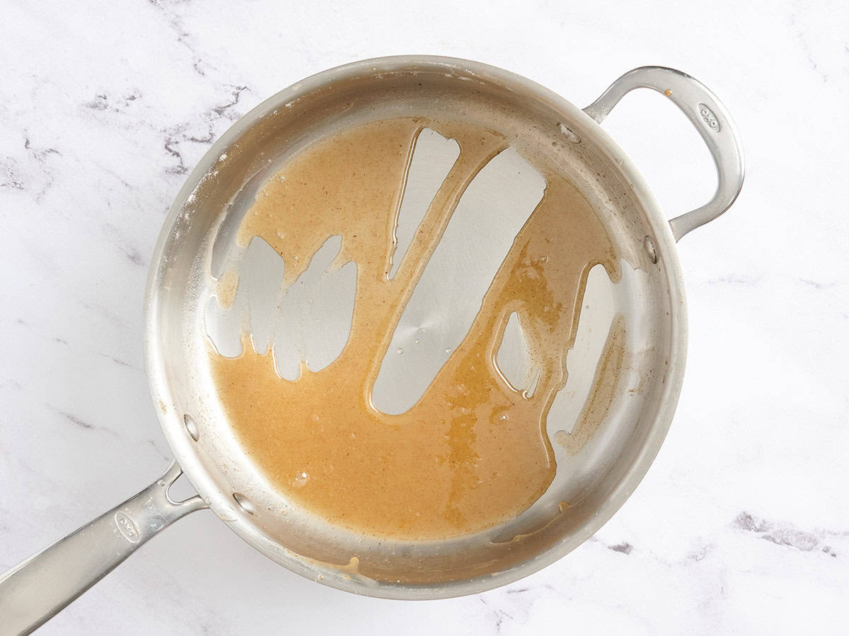 Apple juice in a skillet reduced to make caramel sauce.