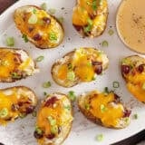 Overhead view of thanksgiving potato skins on a plate with a small bowl of gravy.
