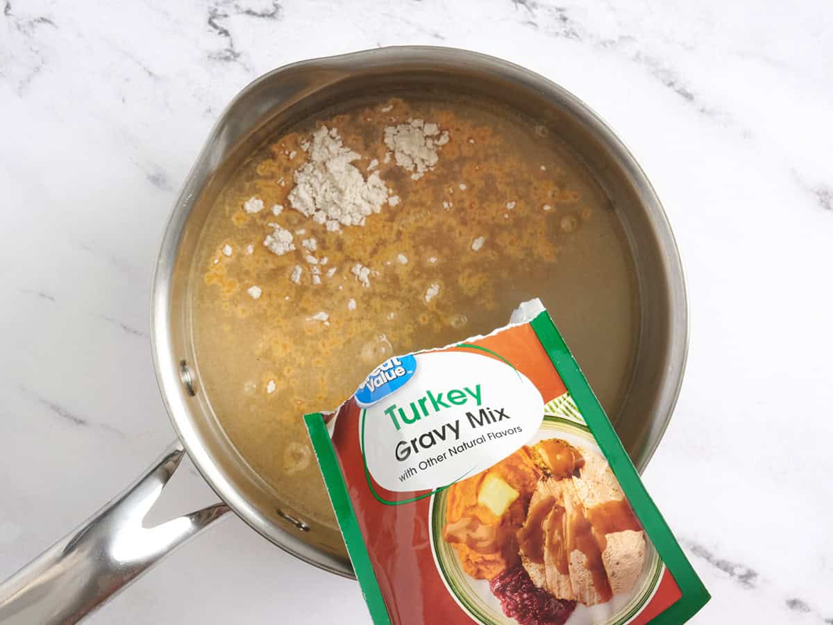 A packet of turkey gravy added to a saucepan.