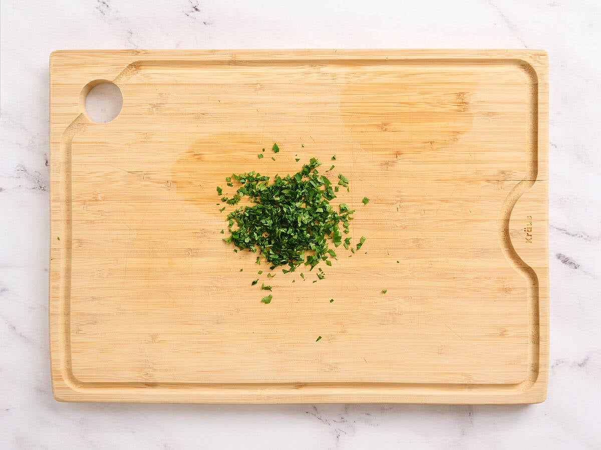 Minced parsley on a wooden cutting board.