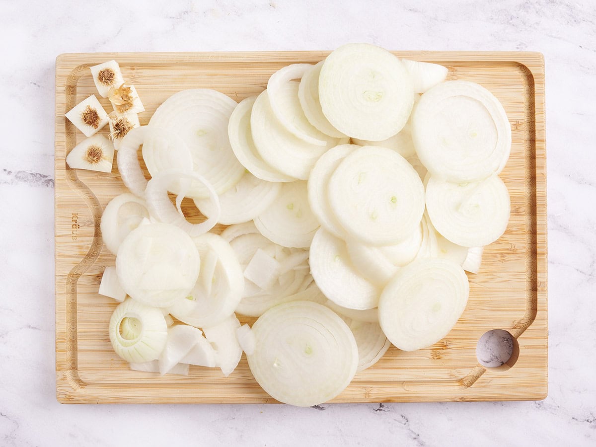Sliced sweet onions on a wooden cutting board.