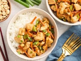Overhead view of two bowls of kung pao chicken with rice.