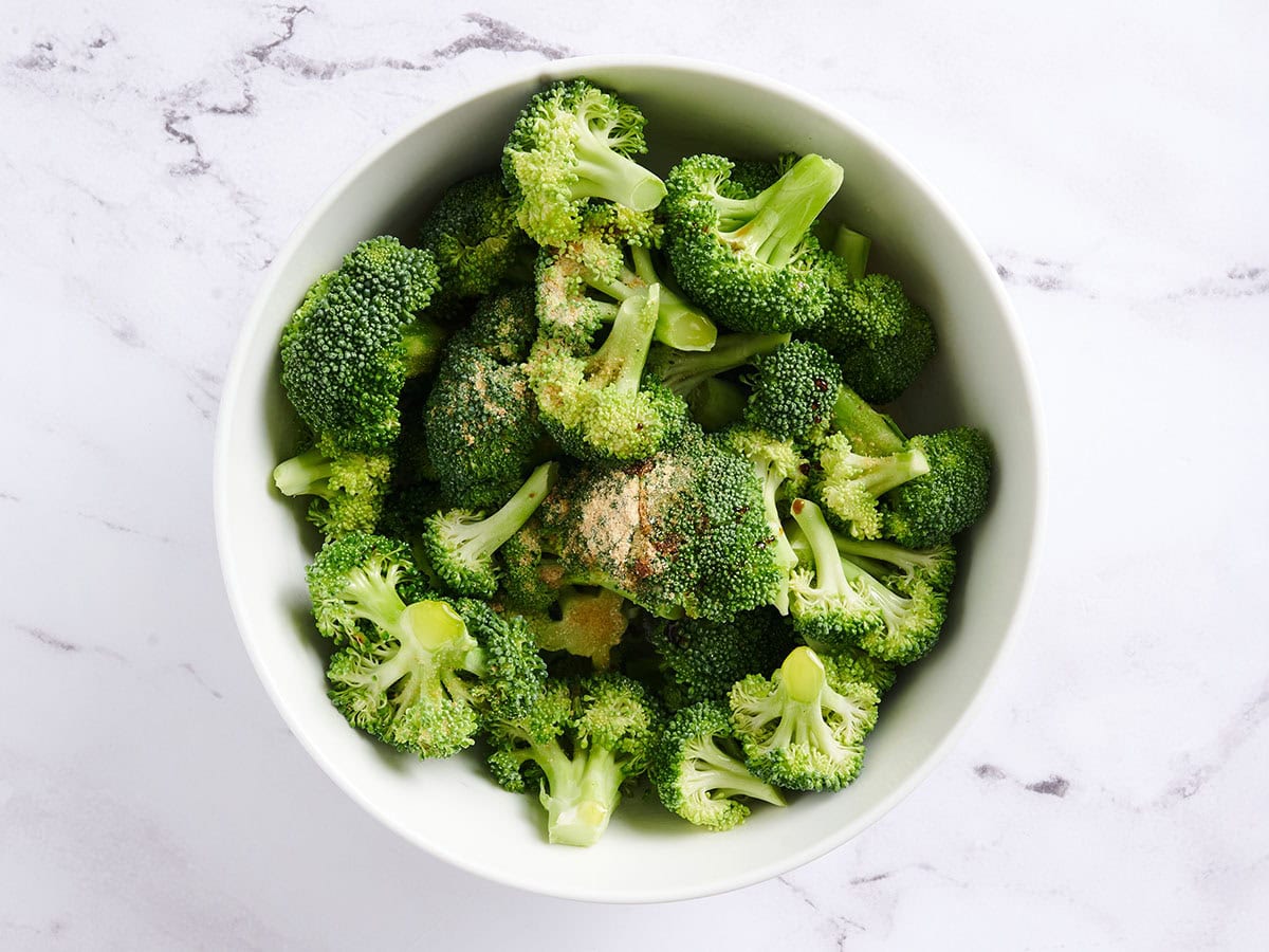 Broccoli florets and seasonings in a bowl.